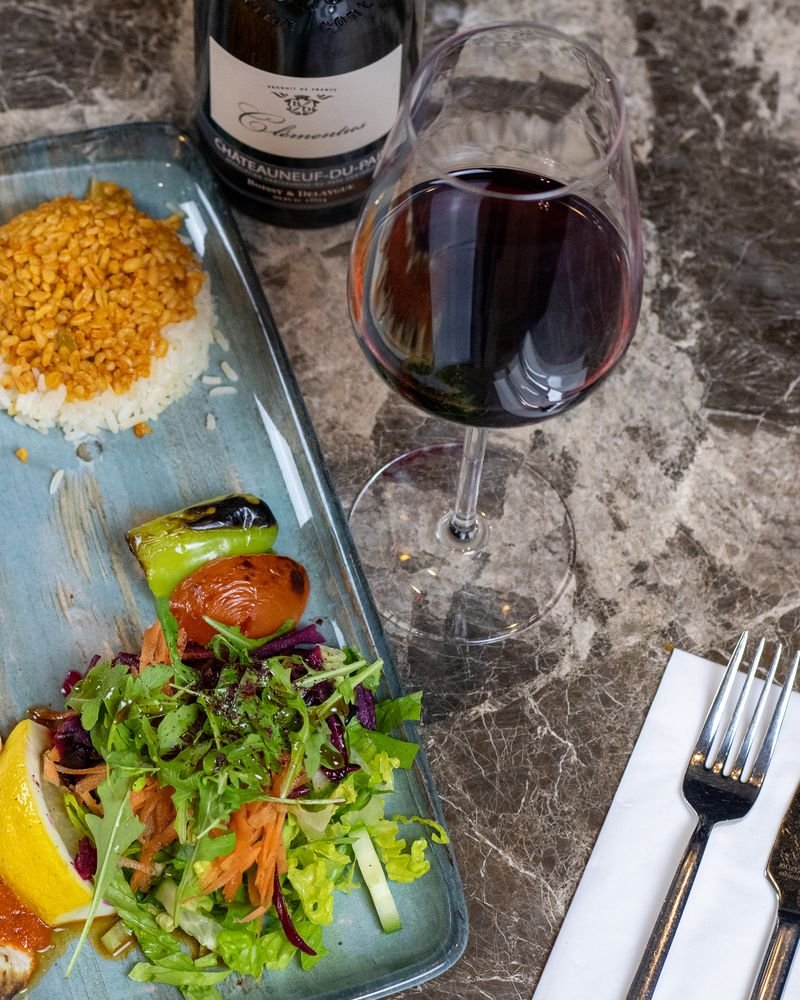 Lamb beyti with bulgur wheat, salad and a glass of red wine