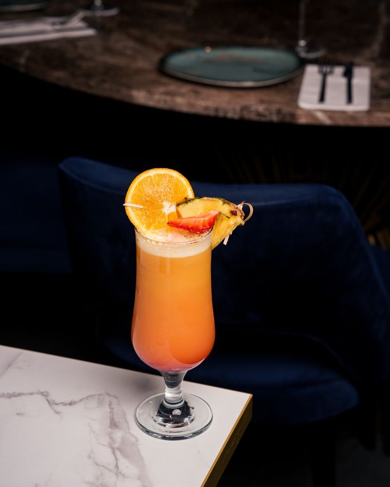 Cocktail garnished with orange and strawberry on the marble bar at Turkoman