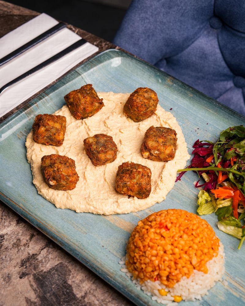 Falafel served on hummus with bulgur wheat and salad