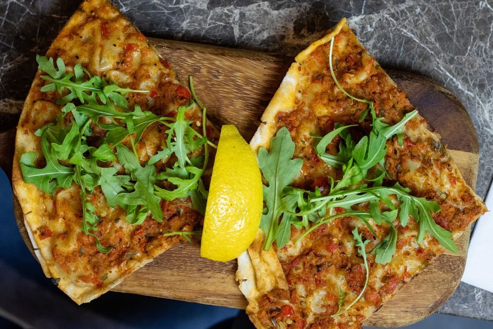 Two lahmacun on a board with rocket and lemon